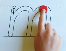 A student tracing an outline letter with a coin